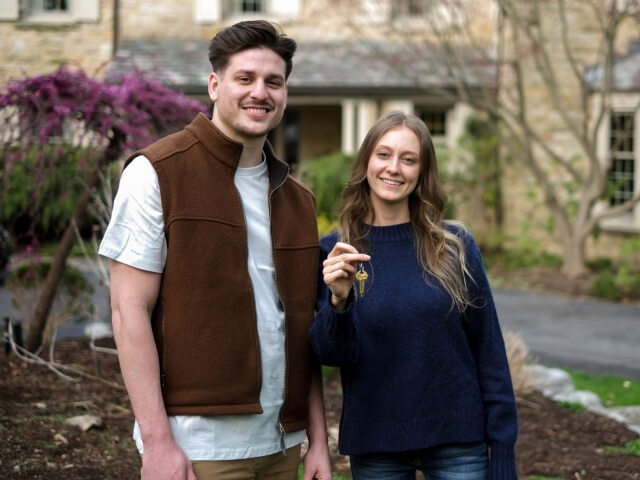 A young couple holding keys to their new house.