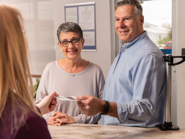 A mature couple handing over documents to a bank employee.