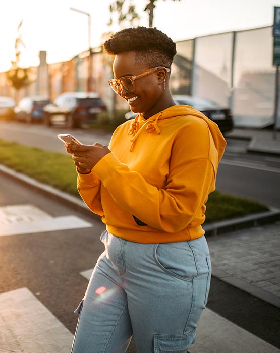 Woman looking at her phone walking across the street.