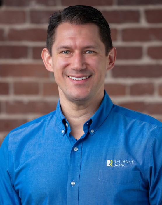 man with brown hair wearing a collared blue shirt